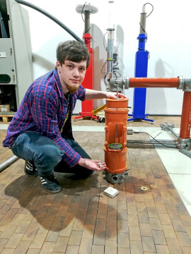 Student Felix Bunk zeigt, wie der Beton durch schnelle Hochspannungspulse so aufgebrochen wird, dass eine saubere Zerlegung von Sand, Steinen und Zementstein geschehen kann.  (Foto: Hochschule Koblenz/Stolz) 