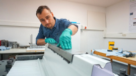 Florian Ilg, wissenschaftlicher Mitarbeiter im Institut für Material- und Bauforschung, bringt eine klebtechnische Verstärkung an auf einem Modell der Deckenunterseite eines Parkhauses (Foto: Wolfram Schlenker) 