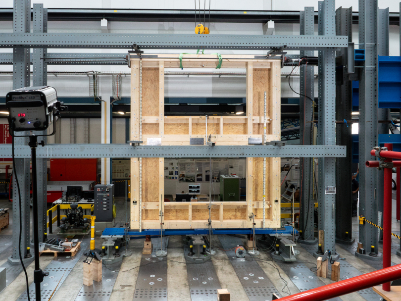 Eine zweigeschossige Hauswand mit Fensteröffnungen wird kontrolliert unter Druck gesetzt. Die Forschenden führten eine Reihe solcher Versuche an der Empa durch. Foto: Empa