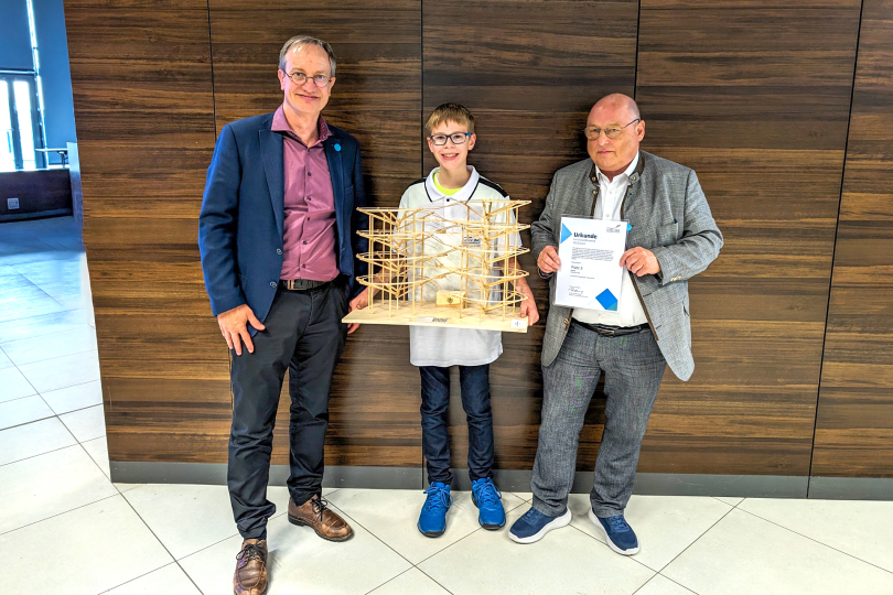 Das Modell „Super 8“ belegt Platz 1 im bayerischen Landesfinale und Platz 3 im Bundesfinale in der Alterskategorie I bis 8. Klasse (Foto: Juror Dr. Michael Smida, Maximilian Öhl und Dr. Ulrich Scholz, Vostand Bayerische Ingenieurekammer-Bau und Bundesingenieurkammer)